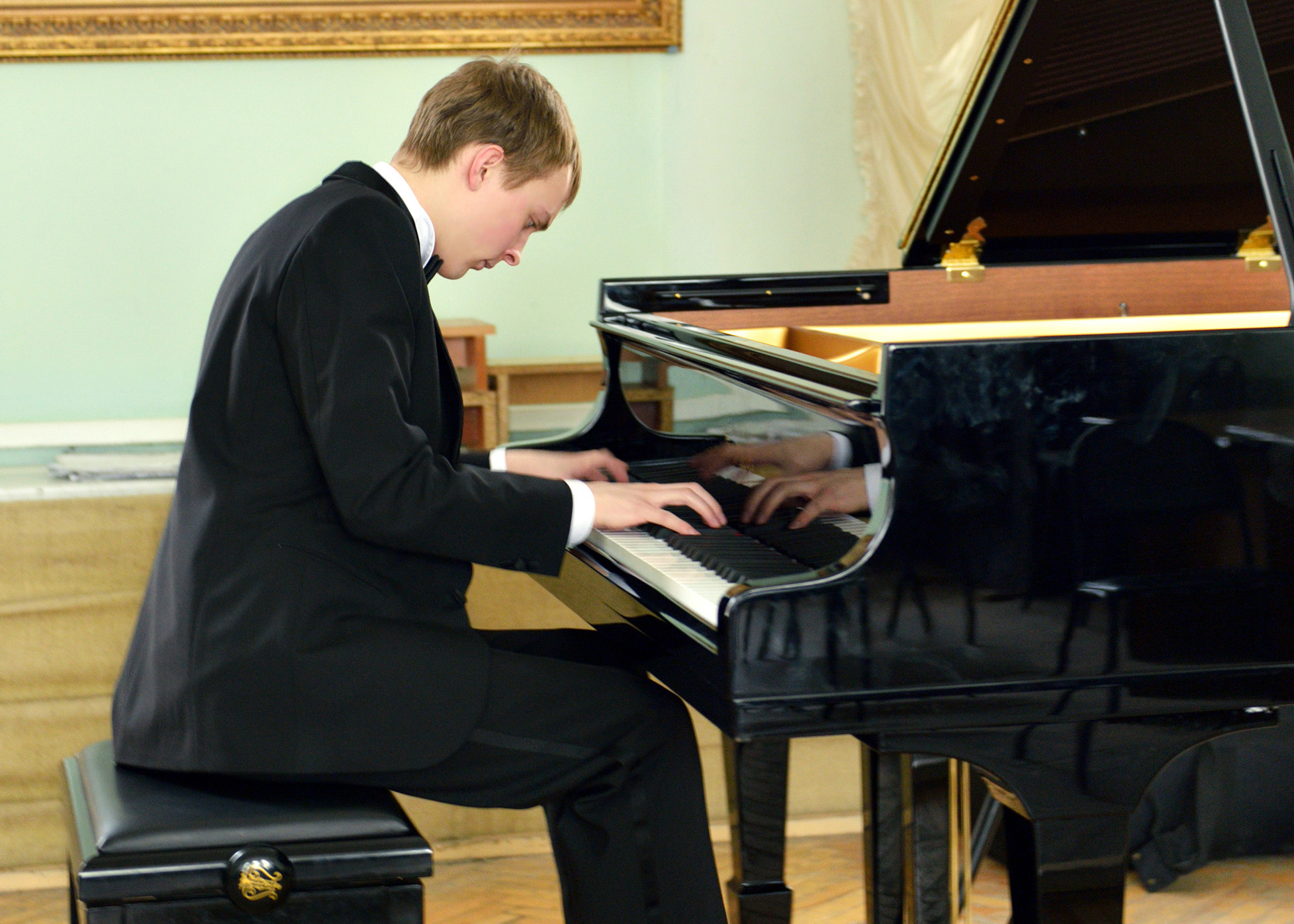 young pianist plays on black grand piano