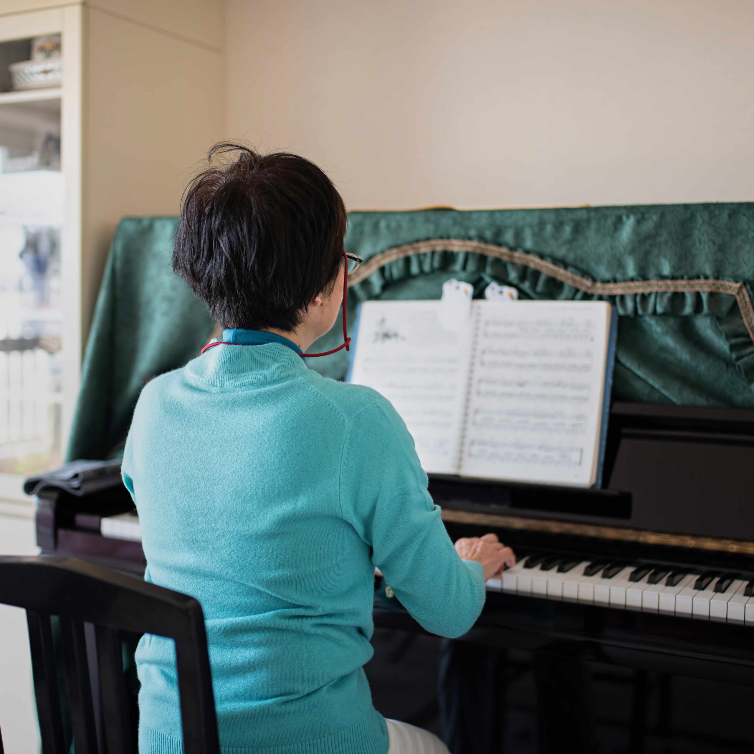 ピアノを弾くシニア女性の後ろ姿
